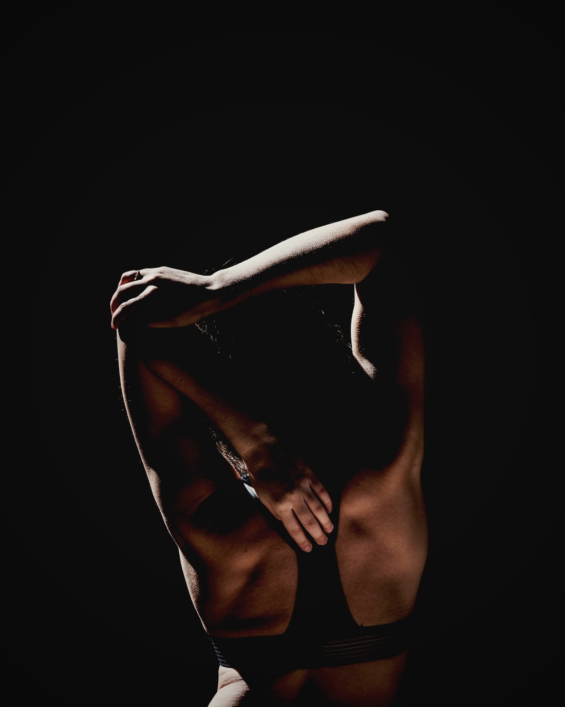 Athlete stretching in a dark studio